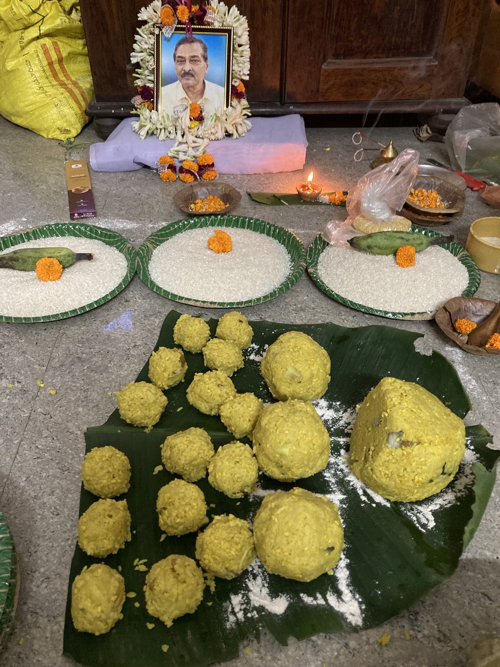 Offerings laid out before his garlanded portrait